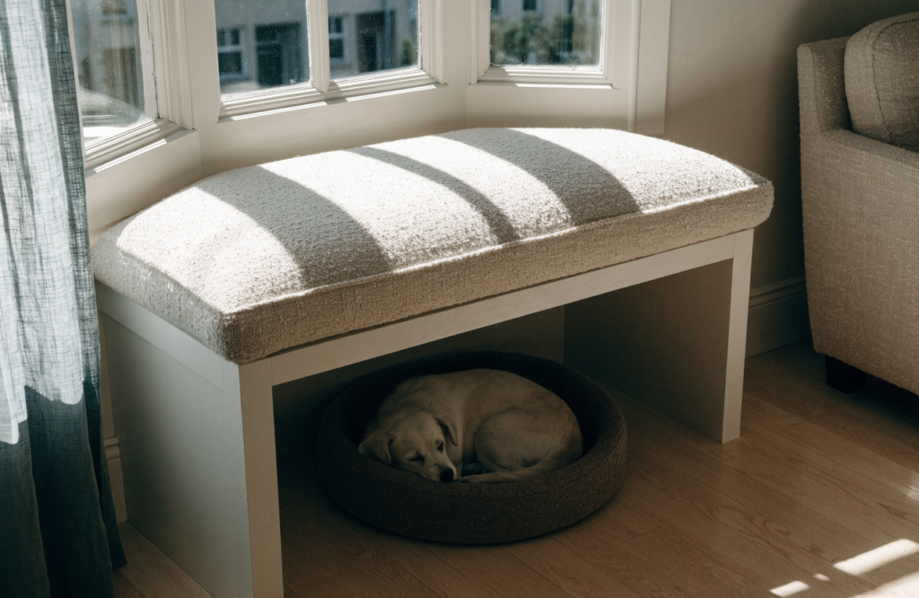 Small dog in a cushioned cubby under a living room window bench