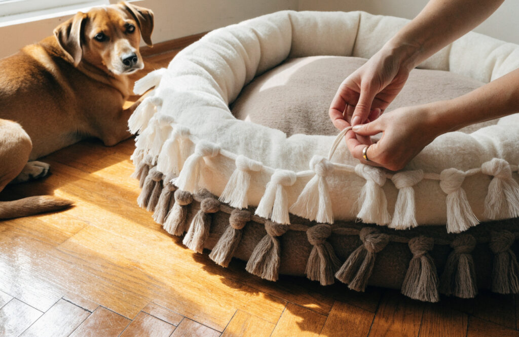 Hands knotting fleece fringe strips closed around the insert of a no-sew dog bed