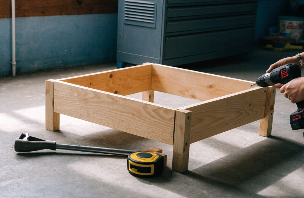 Low pine dog bed frame being screwed together with a drill and clamps