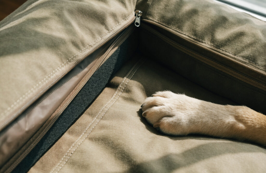 Reinforced corner of a heavy canvas dog bed cover unzipped to show the waterproof liner