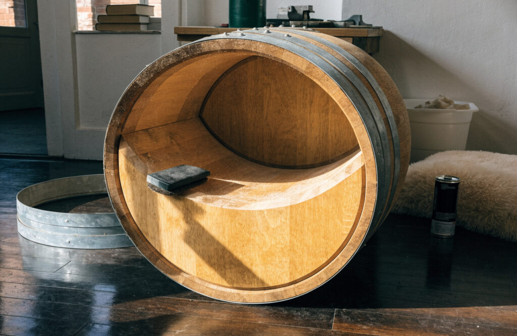 Half oak wine barrel being sanded and finished in a workshop to make a dog bed