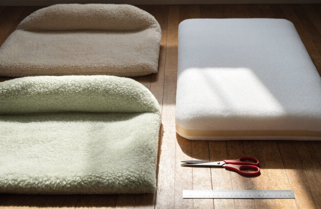 Two fleece panels, a whole pillow insert, scissors and a ruler laid out for a no-sew dog bed